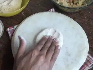 flattened dough ball with fingers